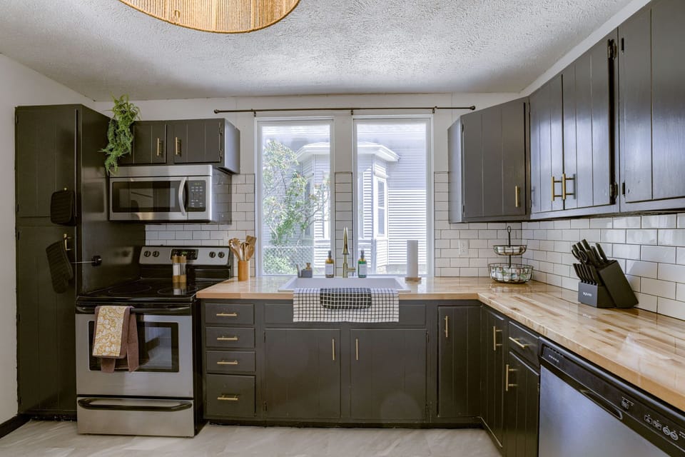 Sleek kitchen with stainless appliances, wood countertops, and subway tile.