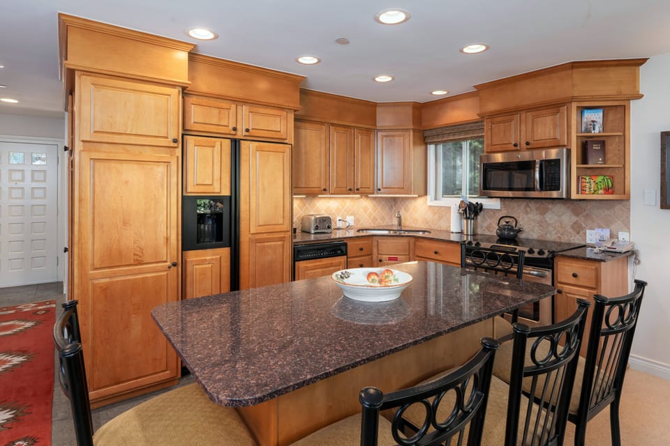 Spacious kitchen with granite countertops and large center island with bar seating for 5. Fully stocked with full size appliances and everything guests need for comfortable meal preparation.