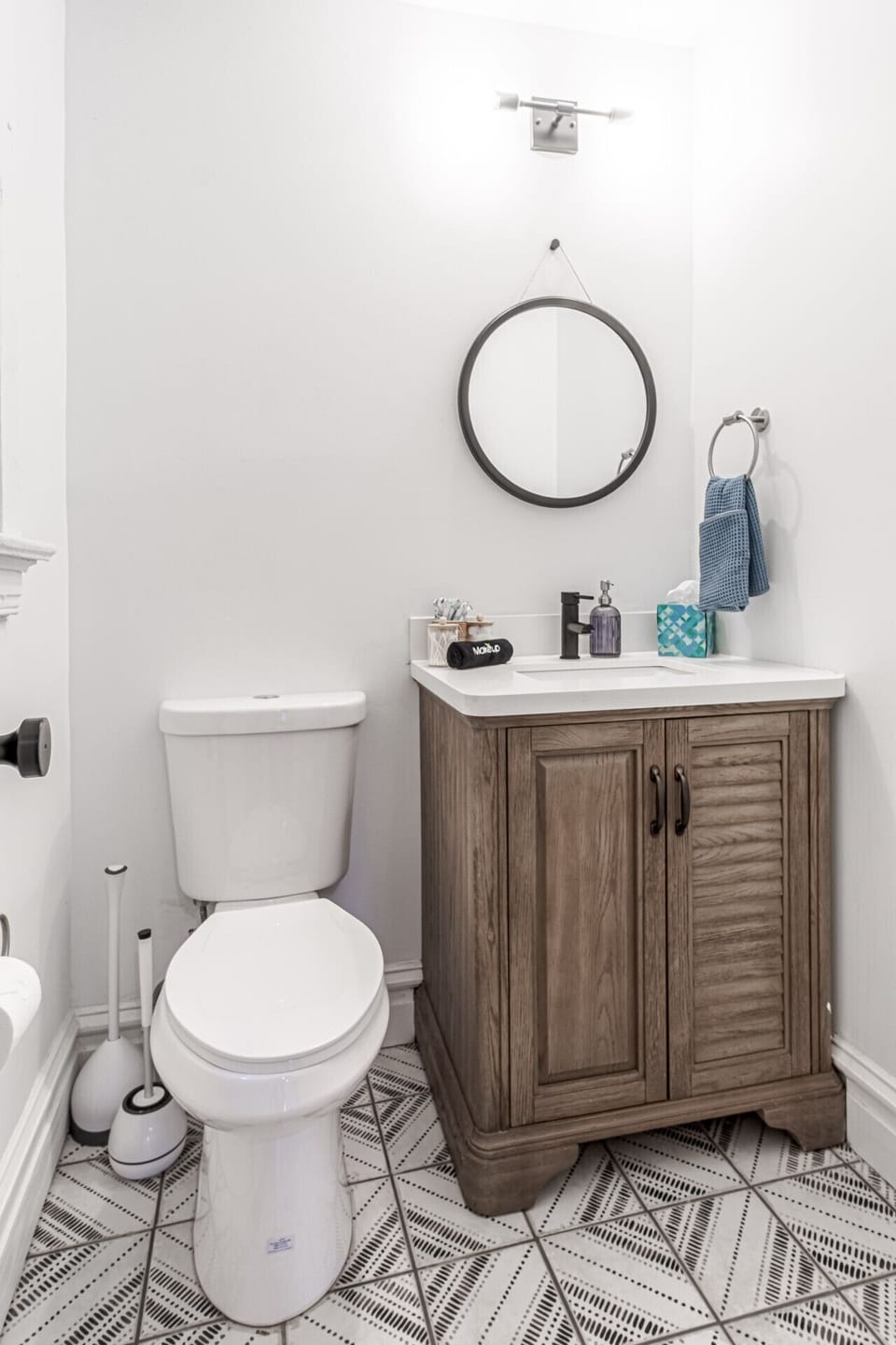 Bath Room: Freshen up before heading out with the convenience of this clean, modern half bath, featuring a rustic wood vanity with ample storage, a crisp white basin, sleek matte black hardware, and a round accent wall mirror.