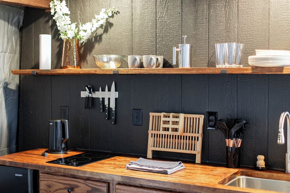 Fully stocked kitchenette with cooktop, mini fridge, cooking supplies, dinnerware