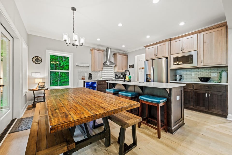 Rustic dining table paired with kitchen island and teal cushioned stools.
