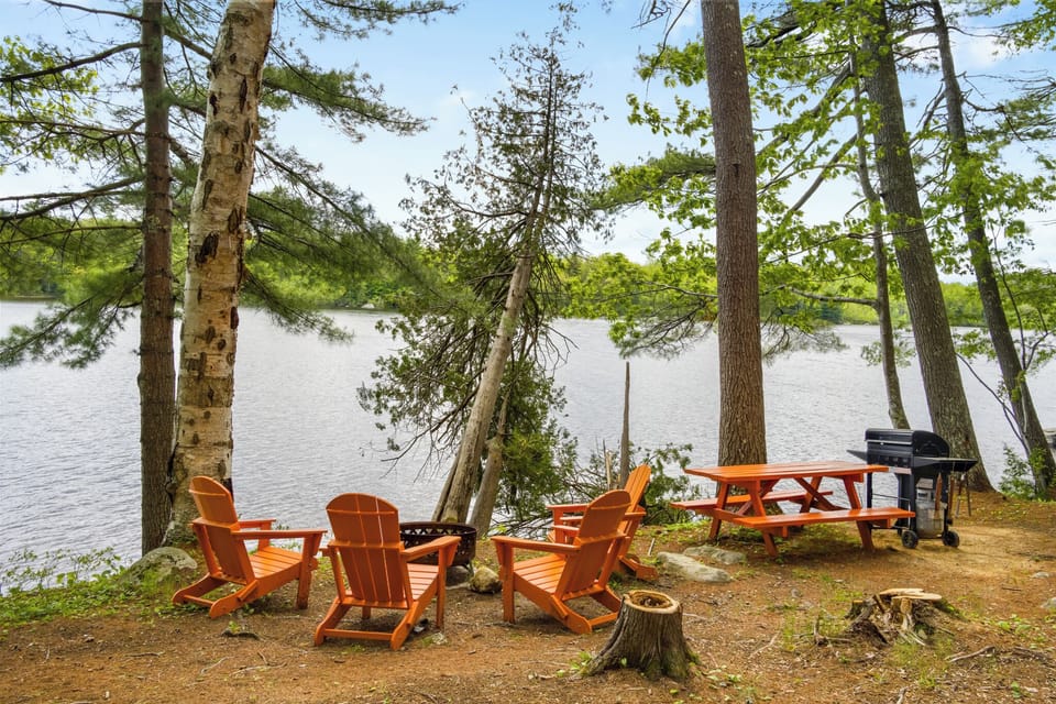 Cozy outdoor dining with wooden chairs and log firepit with laview