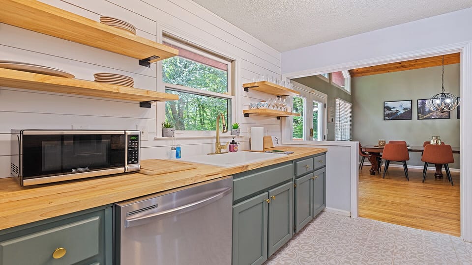 Charming kitchen nook with open shelving, forest views, and modern touches.
