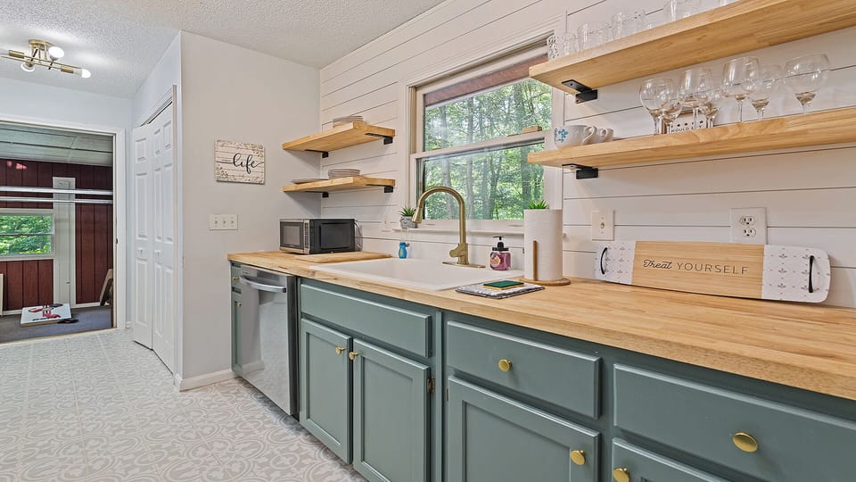 Charming kitchen nook with open shelving, forest views, and modern touches.
