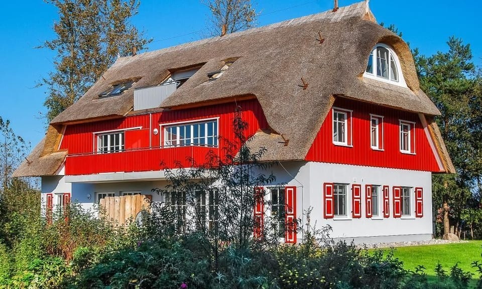 Red vacation house with thatched roof and colorful windows