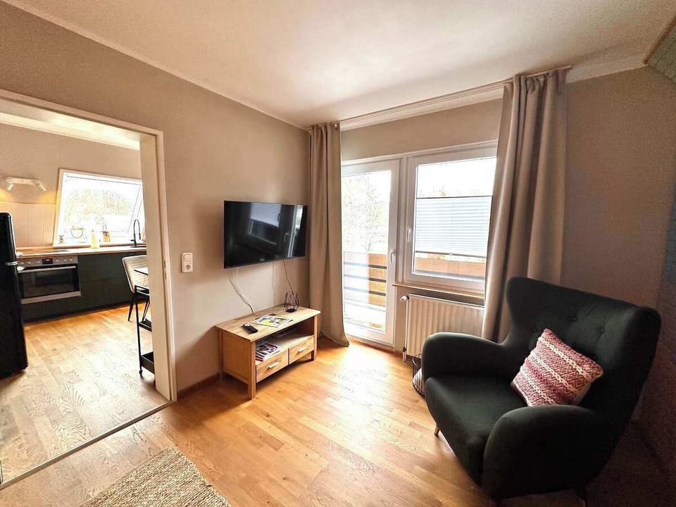 Fernseher mit Sessel und Balkontür im Wohnzimmer.