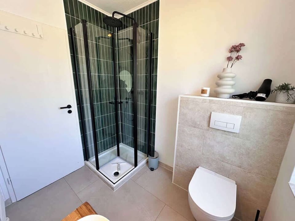 Helles Badezimmer mit Dusche, WC, großem Spiegel und Fenster. 