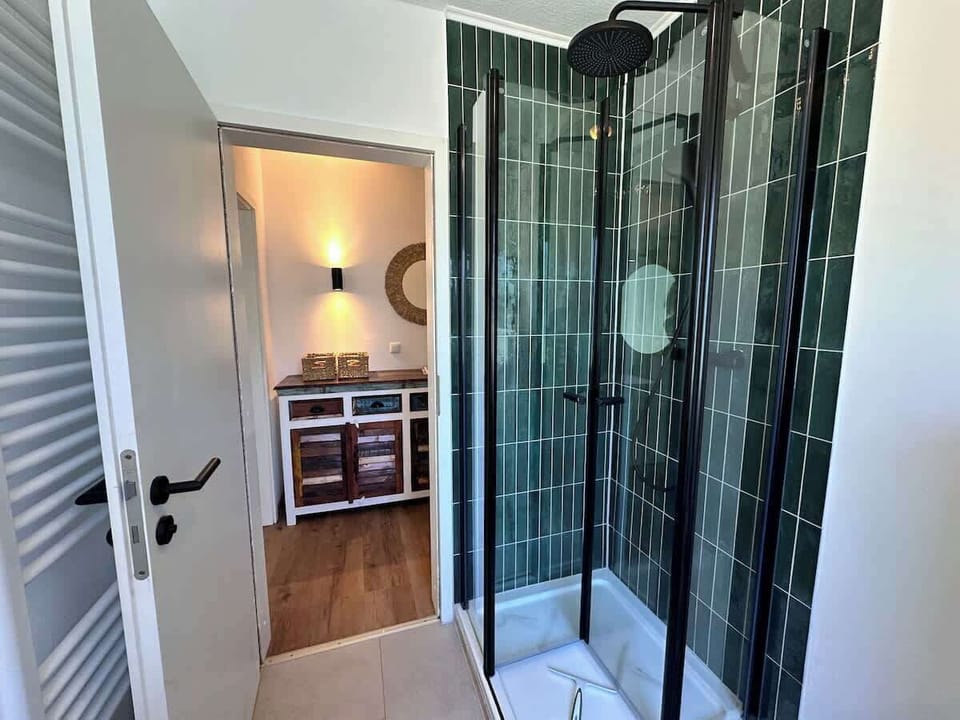 Helles Badezimmer mit Dusche, WC, großem Spiegel Handtuchwärmer und Fenster. 