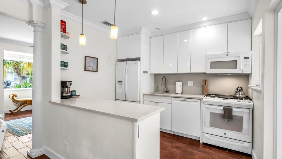 This modern, fully equipped kitchen features sleek white cabinetry, quartz countertops, and all the essentials for your stay—including a filter coffee machine, blender, and serving ware for six. With a gas stove, microwave, and easy access to the patio.