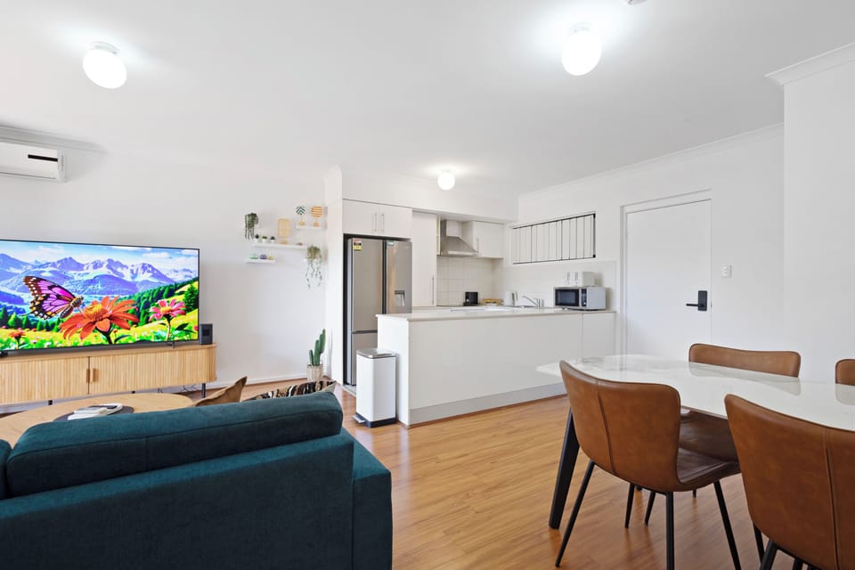 Gather around the modern dining table, perfect for sharing meals and making memories. The open layout seamlessly connects to a comfortable living area with a plush blue sofa, creating an inviting space for relaxation and conversation.