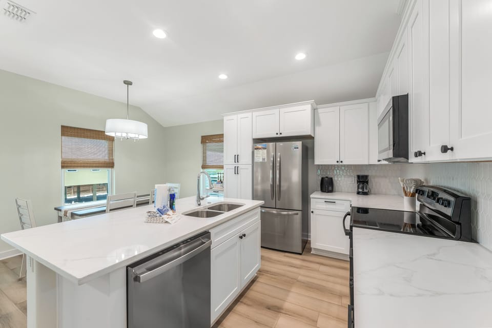 Your spacious gourmet kitchen awaits with pristine white cabinets, gleaming stainless appliances, and a generous island perfect for meal prep.