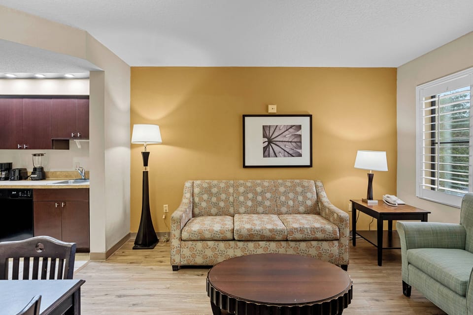 This cozy living area boasts a stylish polka-dot sofa and a comfy armchair, creating a relaxed atmosphere. The warm yellow walls enhance the rich wooden furniture, and soft lighting adds a welcoming glow, perfect for your comfort.
