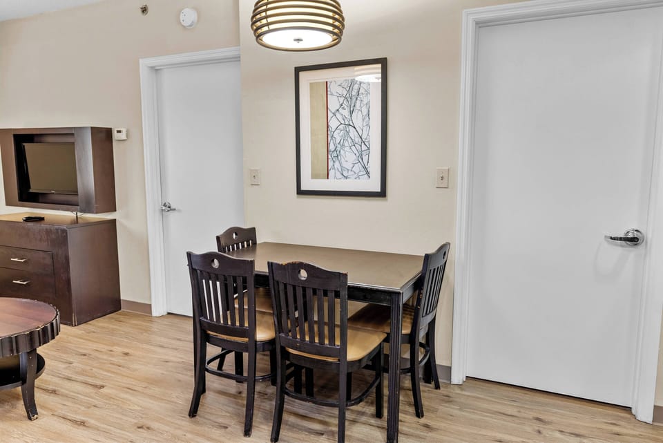 Enjoy a cozy dining nook featuring a sleek wooden table and comfy chairs, ideal for intimate meals or game nights. The warm tones of the flooring and walls create a welcoming vibe, complemented by soft overhead lighting for charm.