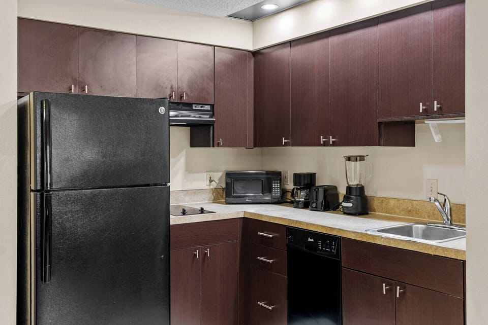 Enjoy a fully equipped kitchen with warm mahogany cabinets and sleek black appliances, complemented by bright countertops perfect for meal preparation.