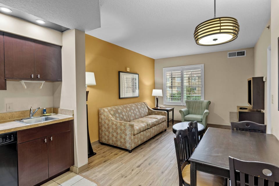 Step into a cozy living area featuring warm golden walls that enhance the natural light filtering through the window. The comfortable sofa invites relaxation, while the sleek dining table offers a perfect spot for meals or games.