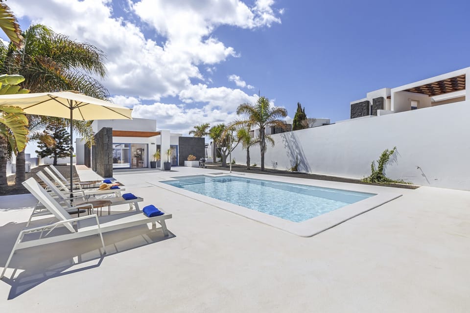 Solarium area by the pool with sunbeds and umbrella.