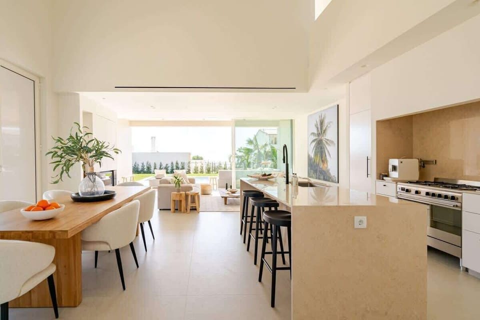 A spacious open-concept layout with seamless flow between kitchen, dining, and living areas. Double-height ceilings and floor-to-ceiling windows bring in natural light, while high-end finishes and stylish furnishings create a warm, modern feel