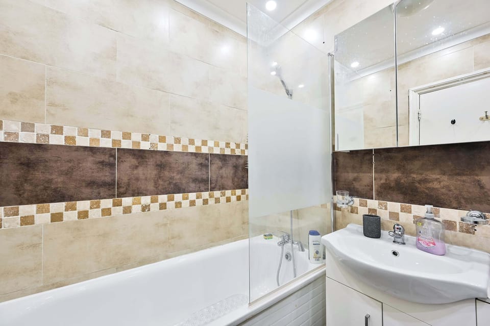 The main bathroom benefits from a toilet, sink and a bath with an overhead shower.