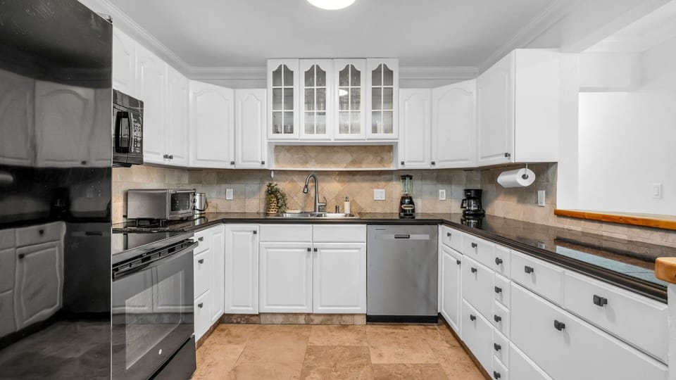 This fully equipped kitchen features black appliances, a filter coffee machine, blender, and plenty of storage. Enjoy both indoor and outdoor dinnerware—perfect for family meals or outdoor dining under the Florida sun.