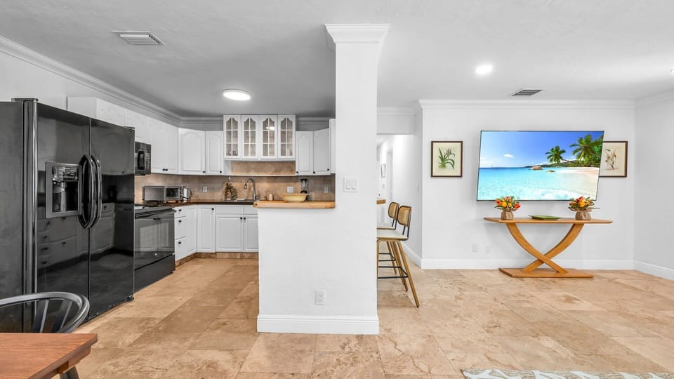 This fully equipped kitchen features black appliances, a filter coffee machine, blender, and plenty of storage. Enjoy both indoor and outdoor dinnerware—perfect for family meals or outdoor dining under the Florida sun.