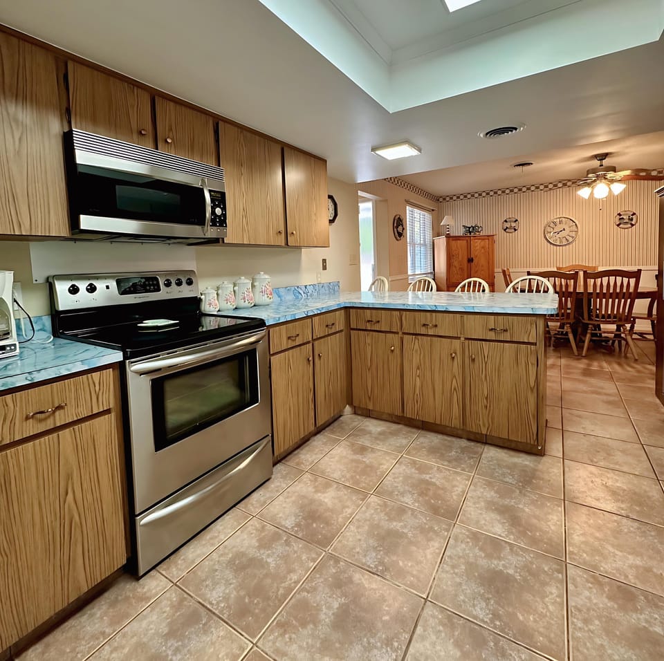 Bright and fully equipped kitchen with stainless steel stove and microwave, plenty of counter space, and classic wooden cabinetry. Whether you're preparing a full meal or heating up leftovers, everything you need is right at your fingertips.