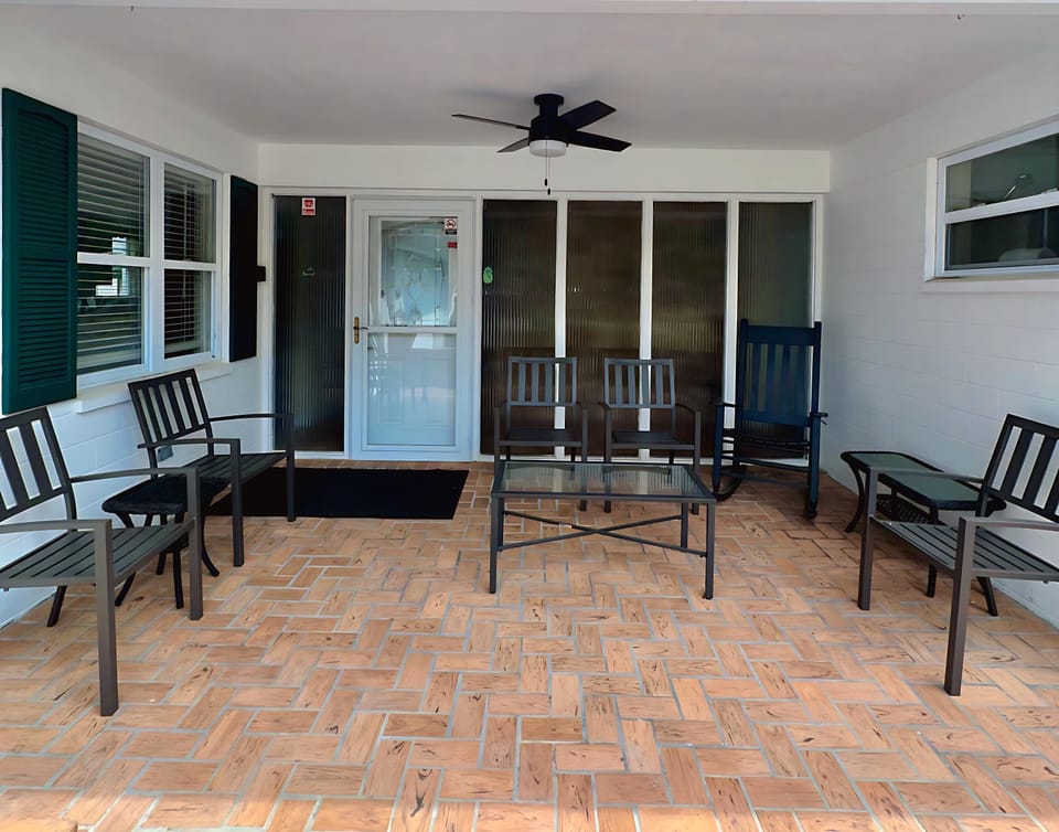Kick back on the covered patio with plenty of seating, a ceiling fan for comfort, and a cozy brick floor — perfect for morning coffee or evening conversations in the fresh air!