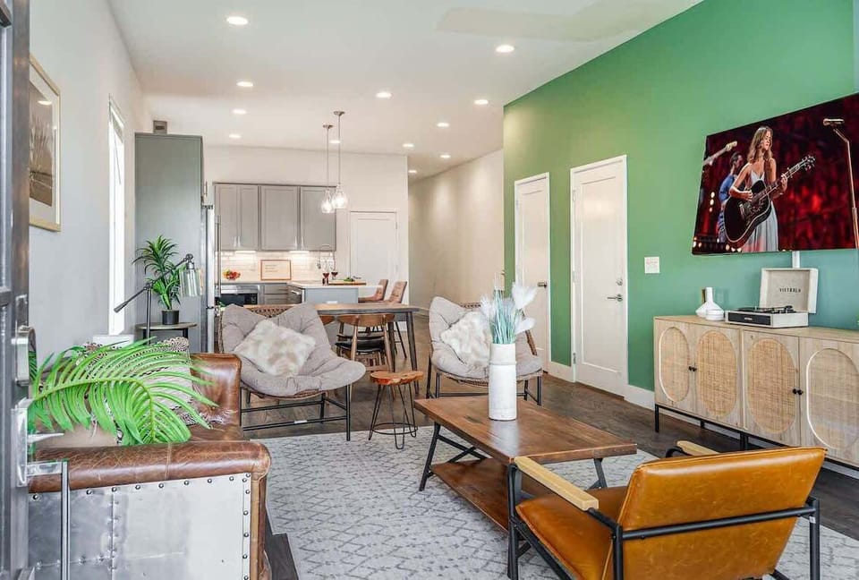 Unit 1: Welcoming living area with a vibrant green accent wall, large Smart TV, and plush seating arranged to take in the serene outside views.