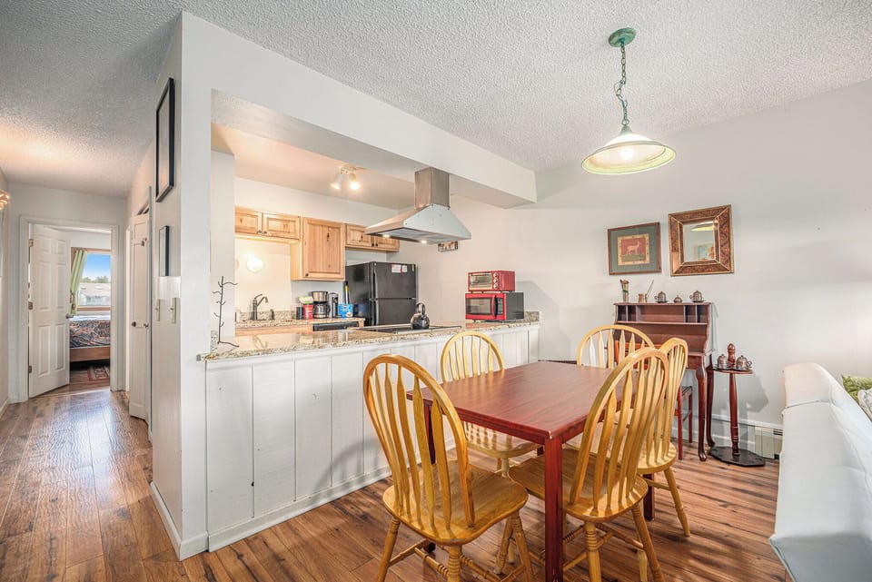 - Cozy dining space with seating for four, ideal for casual meals and game nights
- Overlooks a well equipped kitchen with granite counters and breakfast bar
- Warm wood tones and pendant lighting enhance the inviting mountain vibe