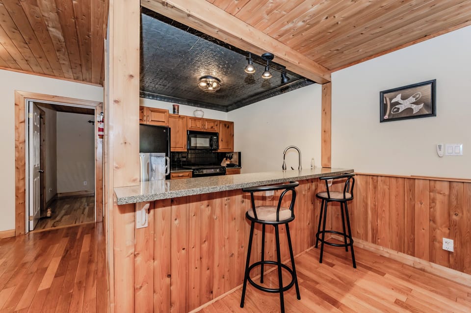 Enjoy casual dining at the breakfast bar in a wood-paneled cottage kitchen—ideal for morning coffee or laid-back cooking sessions.