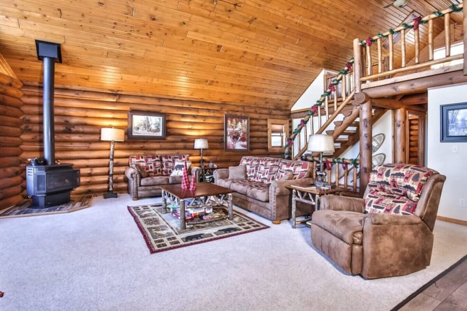 Gather in the warm glow of our log-beamed living room, where plush lodge-style sofas and a gas fireplace stove create the perfect setting for relaxing after a day on the lake or trails. The open lofted ceiling, natural woodwork, and Northwoods decor make 