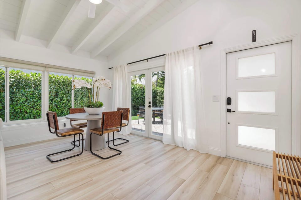 Bright dining area with modern furniture and garden views through large windows and glass doors.