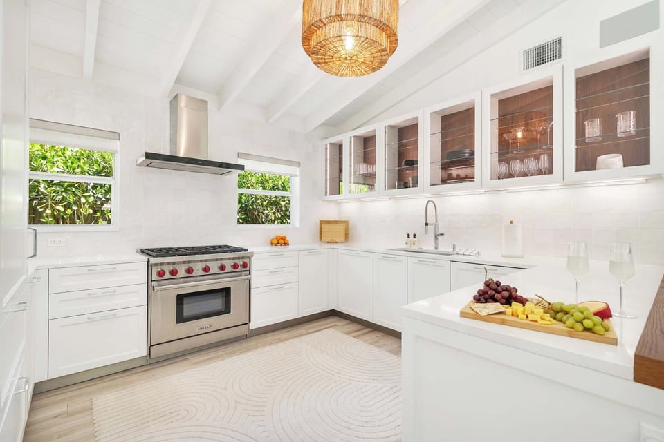 Bright modern kitchen with stainless steel appliances and glass-front cabinets.