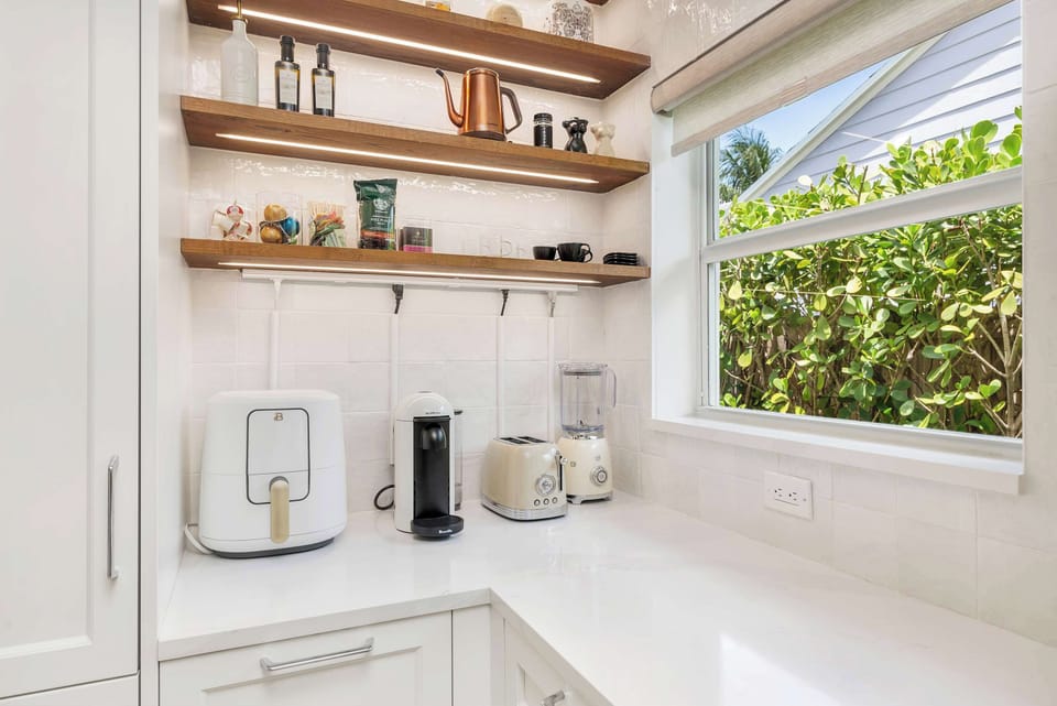modern kitchen corner with coffee maker, toaster, and blender by a window overlooking greenery