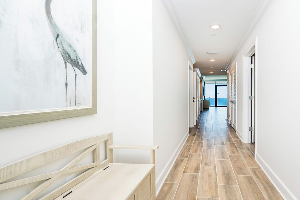 Step into a welcoming hallway featuring a decorative bench and artwork, leading to a stunning beach view