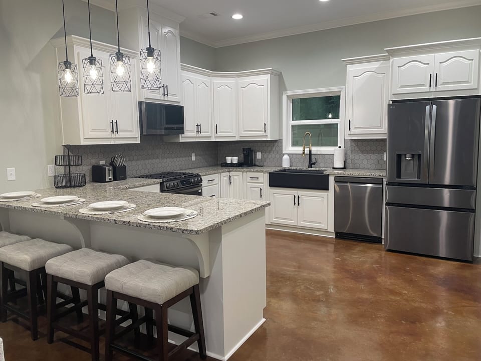 Full kitchen with five bar stools and open concept living room plan. 
