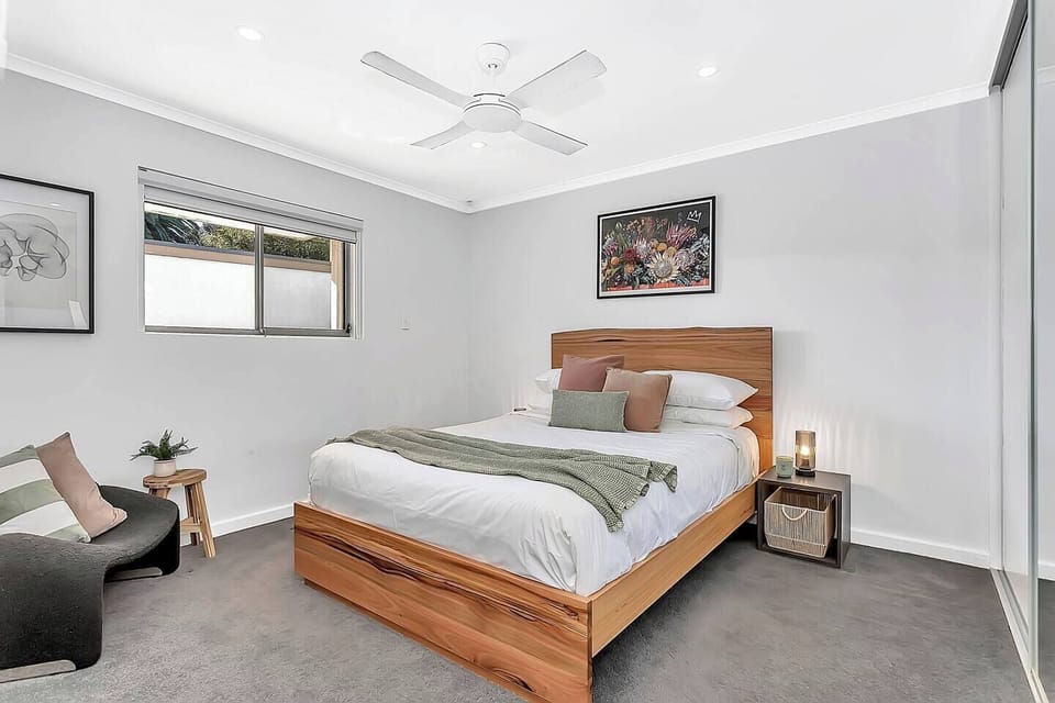 Recharge in the primary bedroom, featuring a queen bed, a stylish chair, a built-in wardrobe and a ceiling fan to keep the room cool and comfortable.