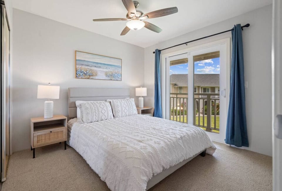 Bright and welcoming second queen bedroom featuring calming coastal décor and sliding glass doors that open to a charming balcony.