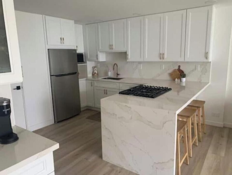 Quartz waterfall peninsula with 3 Tibetan barstools for seating at the counter.