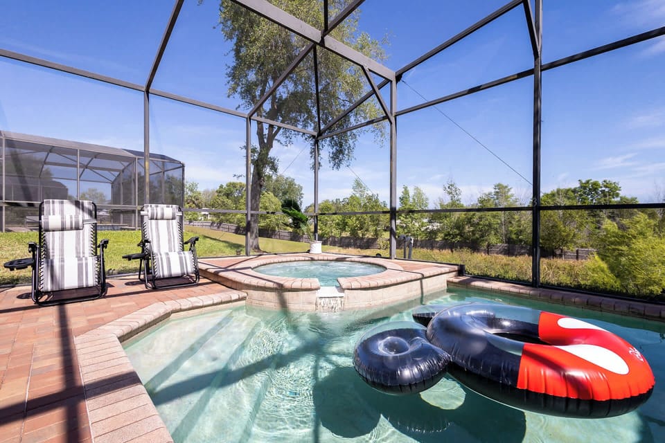 Back screened in patio with outdoor seating, grill, pool, and hot tub