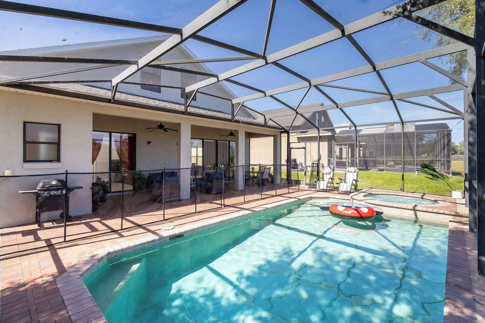 Back screened in patio with outdoor seating, grill, pool, and hot tub