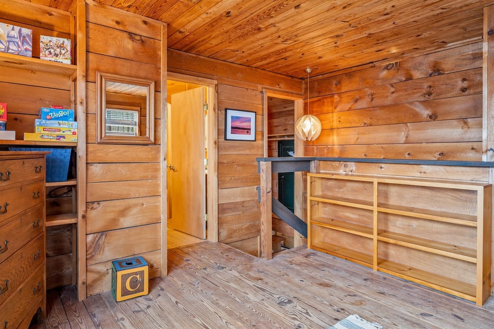 Cozy, rustic bedroom with wooden walls and ample storage. Perfect for unwinding in a tranquil, natural setting. 🛏️🌲