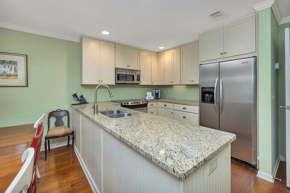 Kitchen with granite island, white cabinets, and stainless appliances