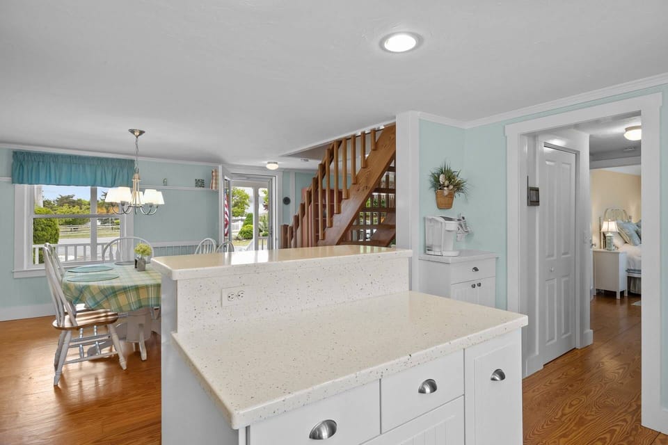 Another view of the kitchen island, dining table, and Keurig machine
