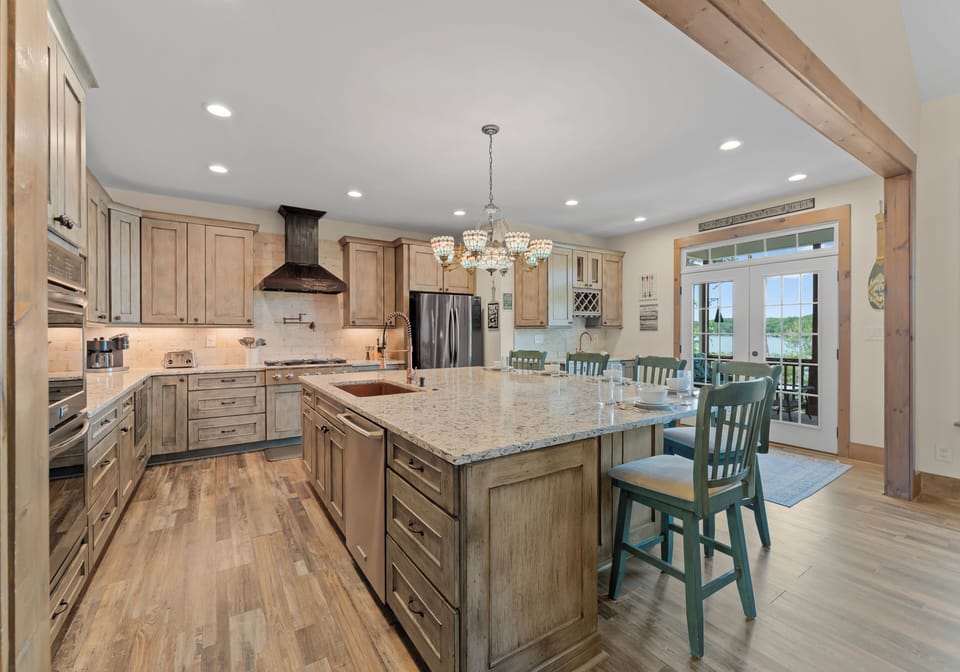 Gourmet kitchen with island seating, wood cabinets, and stainless steel appliances.
