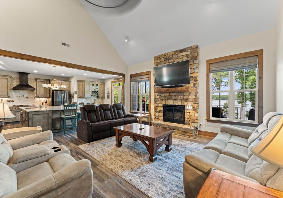 Spacious living room with high ceilings, stone fireplace, and large windows.