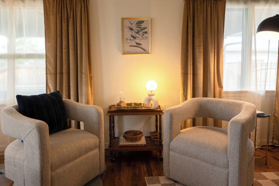 Twin chairs with a glowing table lamp and framed wall art.