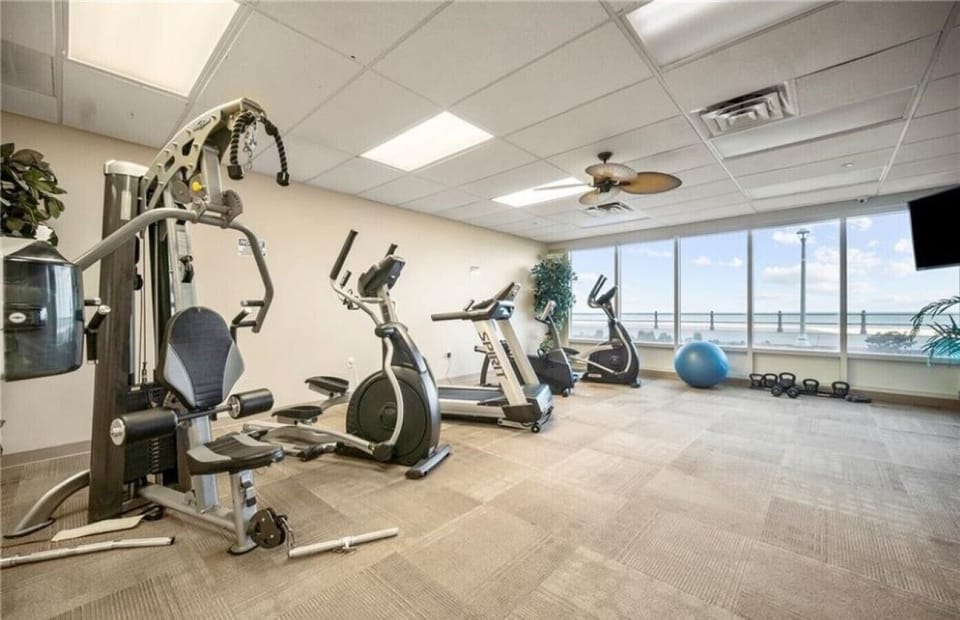 Fitness center on-site with cardio machines and oceanfront windows.