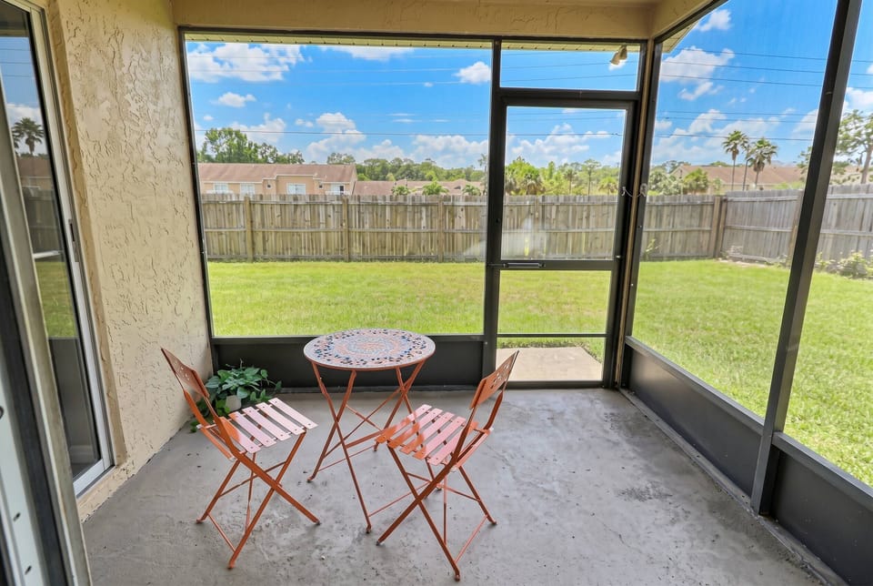 Relax in this cozy screened-in porch, bathed in soft natural light. Enjoy charming bistro seating and tranquil views of the lush green lawn, ideal for peaceful mornings or unwinding in the evenings.