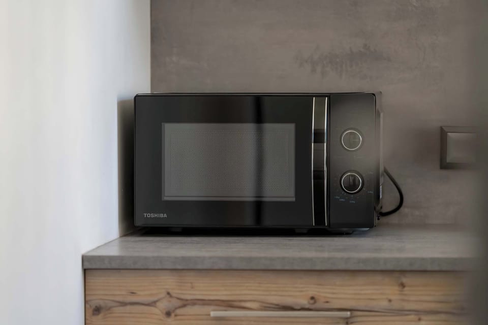 The microwave set against a concrete-style wall is a practical convenience for quick snacks and reheated meals.