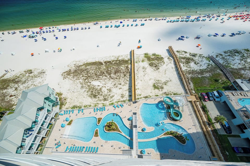 Vibrant pool area with a gradual entry, lazy river, and fun winding waterslide, perfect for sunbathing and relaxation